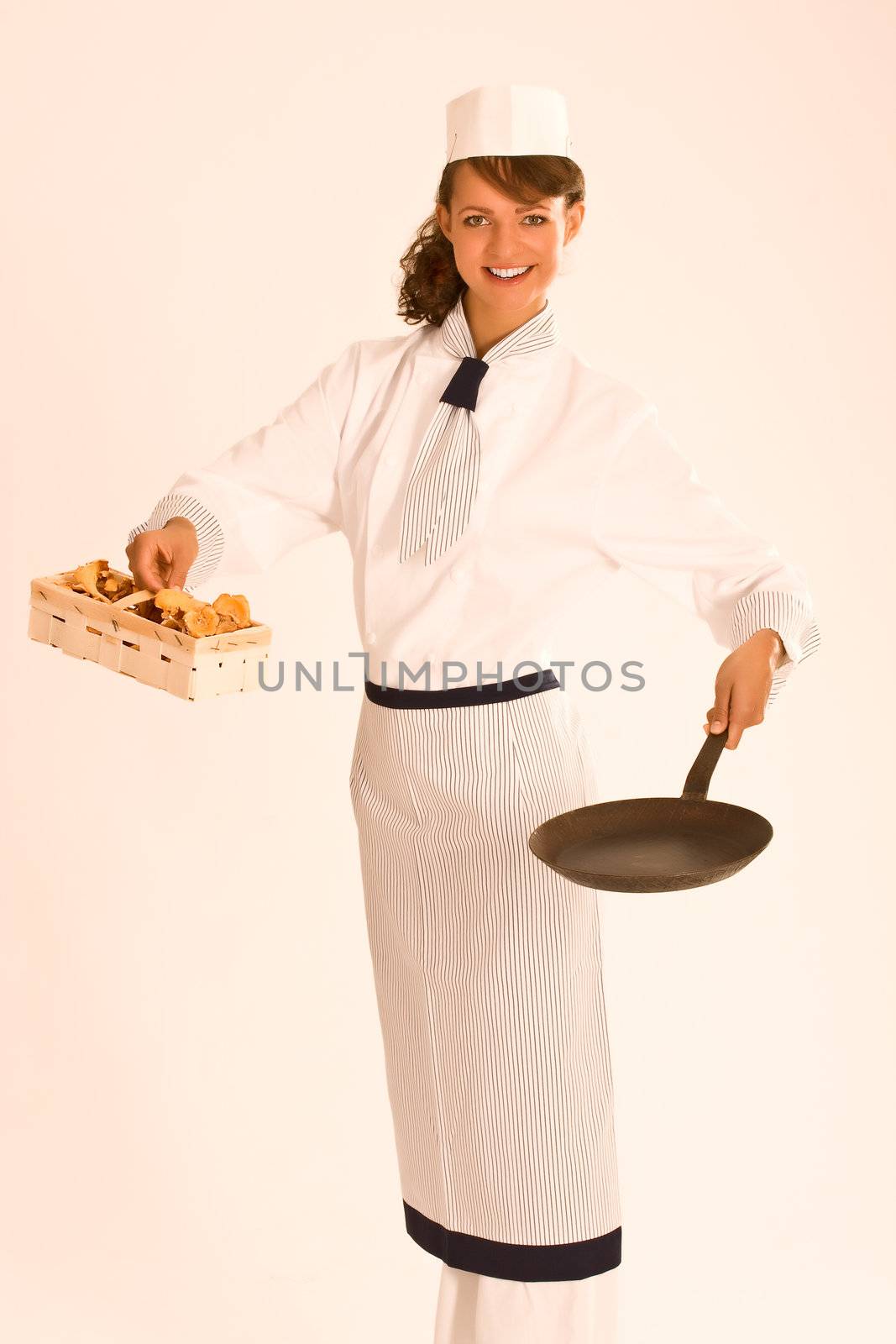 female chef with chanterelle mushrooms, pan and apron by STphotography