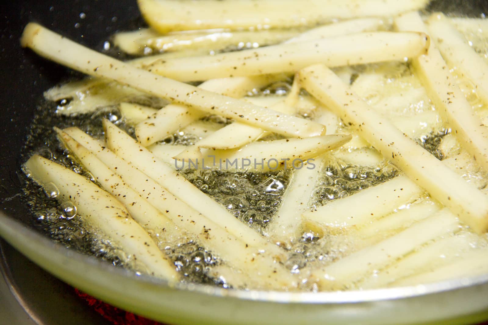 Frying french fries in a pan with oil over a hot stove