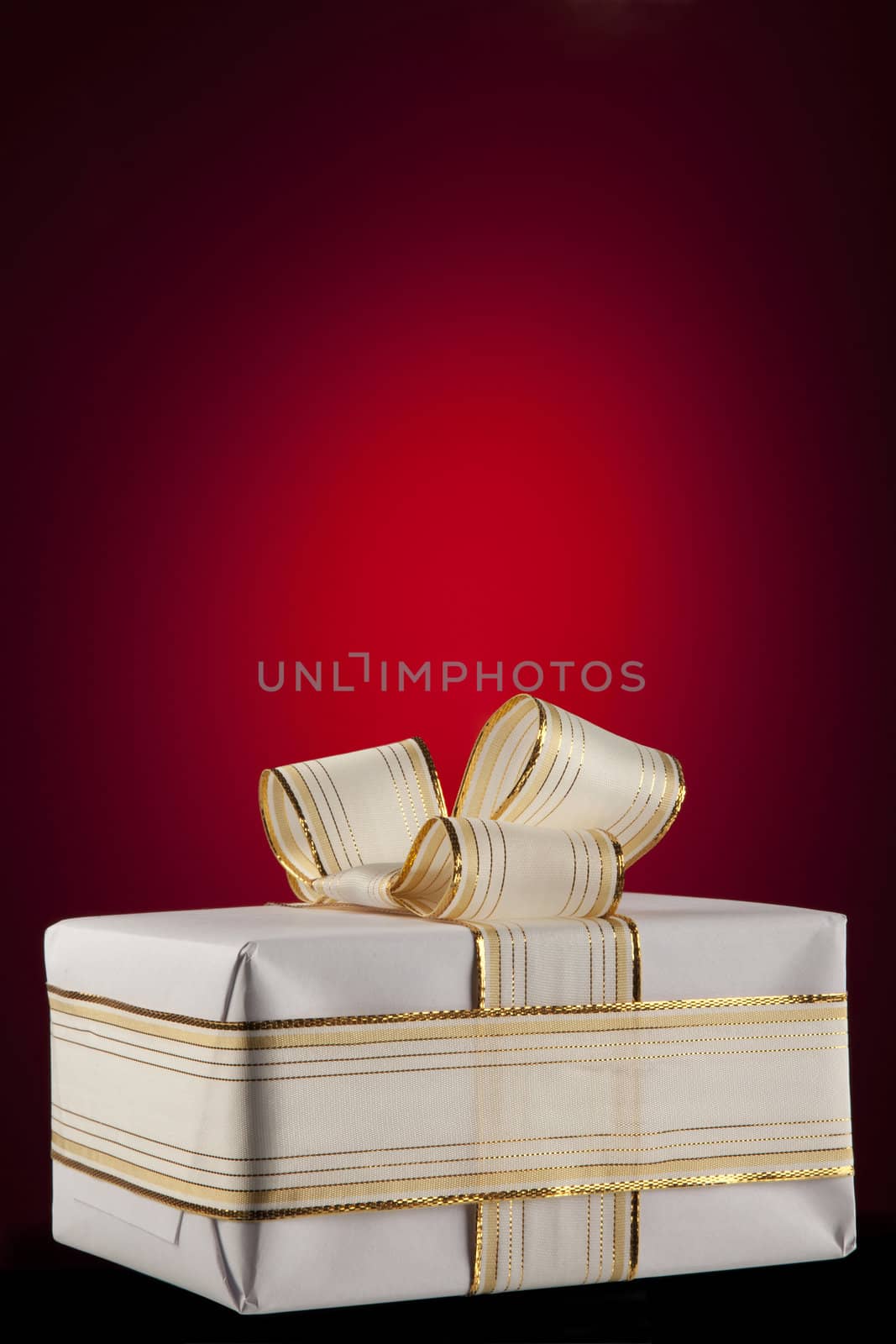 White gift box with bow ribbon on red background 