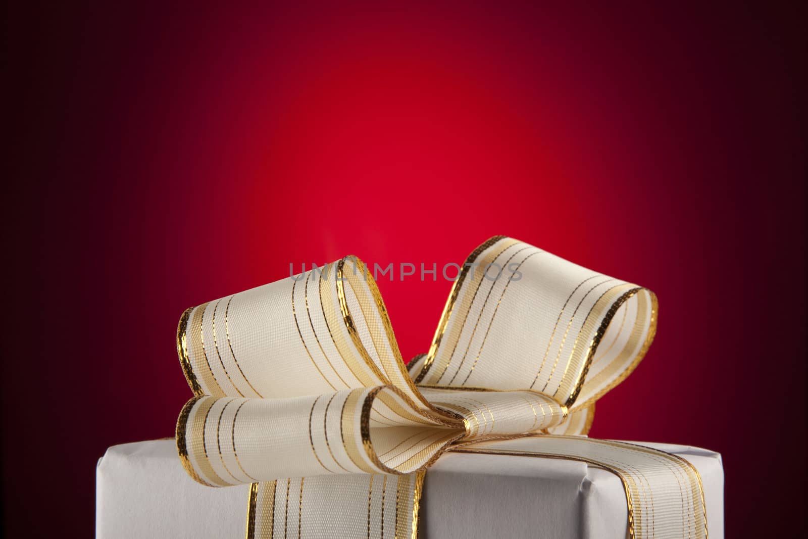 White gift box with bow ribbon on red background 