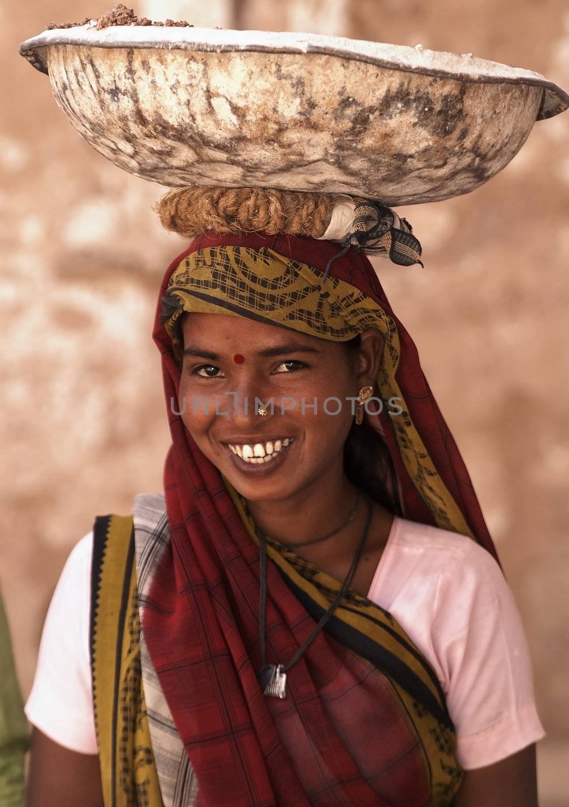 Indian woman labourer carrying metal bowl filled with cement