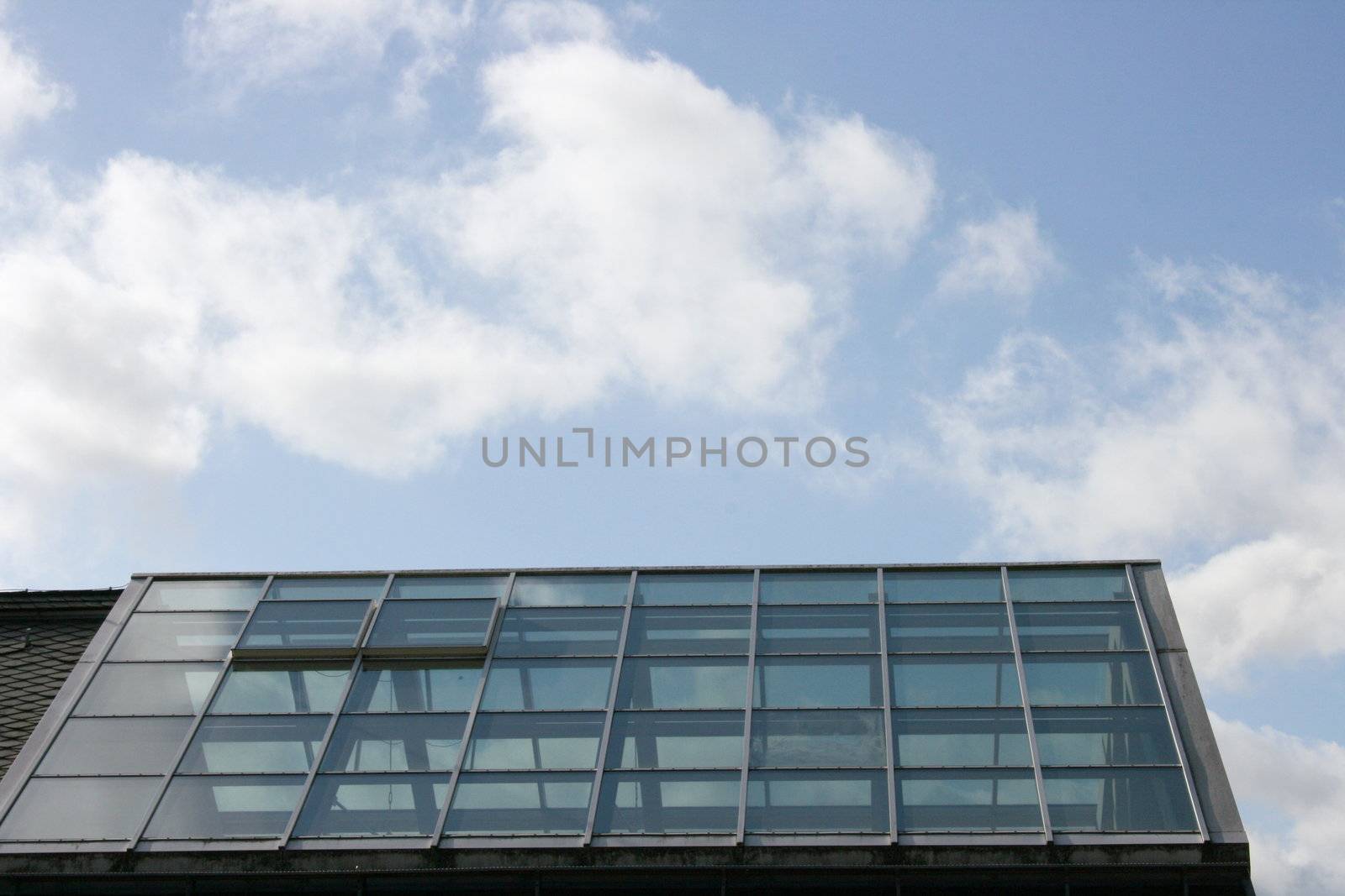 Glasdach eines Gebäudes,mit blauem Himmel im Hintergrund 	
Glass roof of a building, with blue sky background