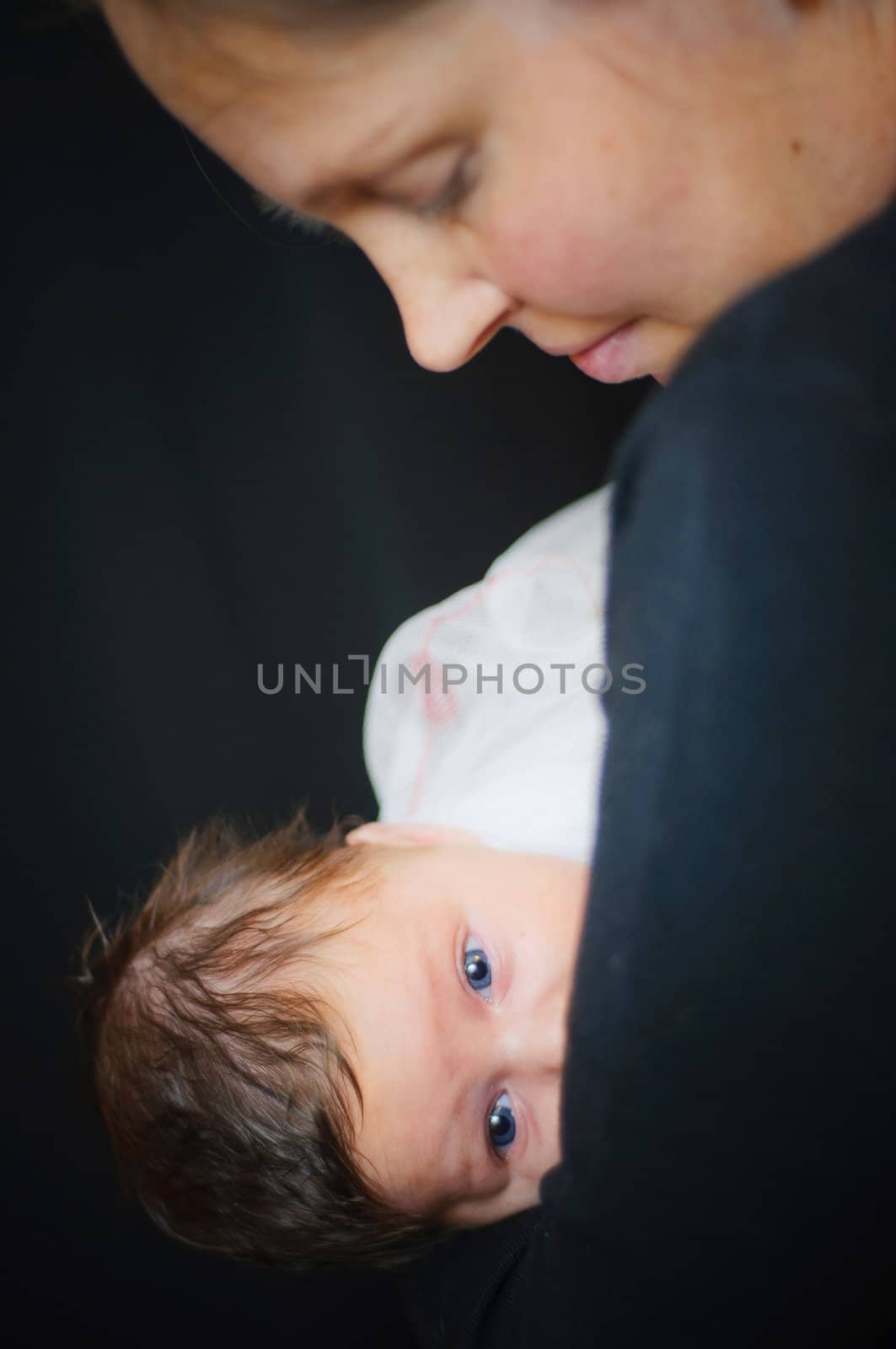 Happy cute infant boy lying on his mother hands