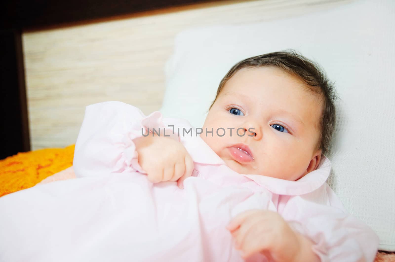 Beautiful cute baby girl is lying in a bed.
