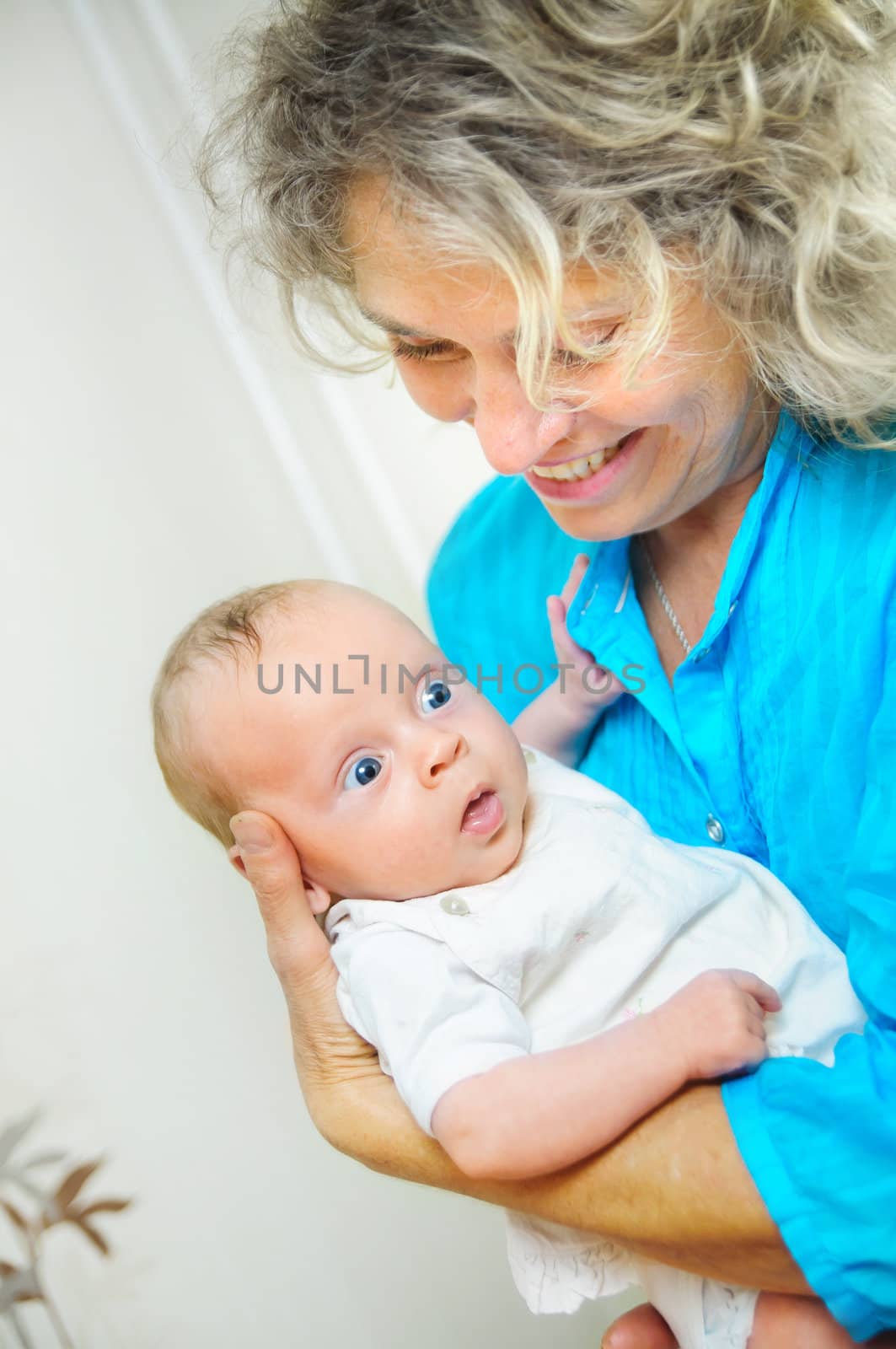 Happy cute infant boy lying on his grandmother hands