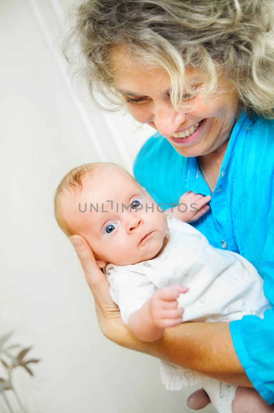 Happy cute infant boy lying on his grandmother hands