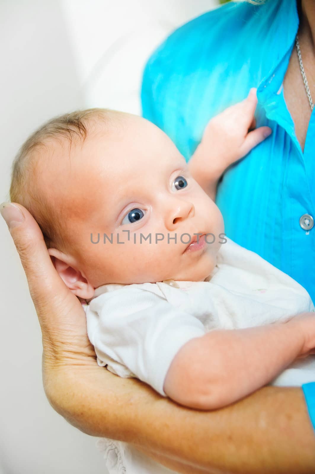 Happy cute infant boy lying on his grandmother hands