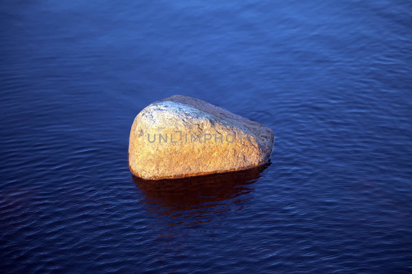 Stone on blue water in evening