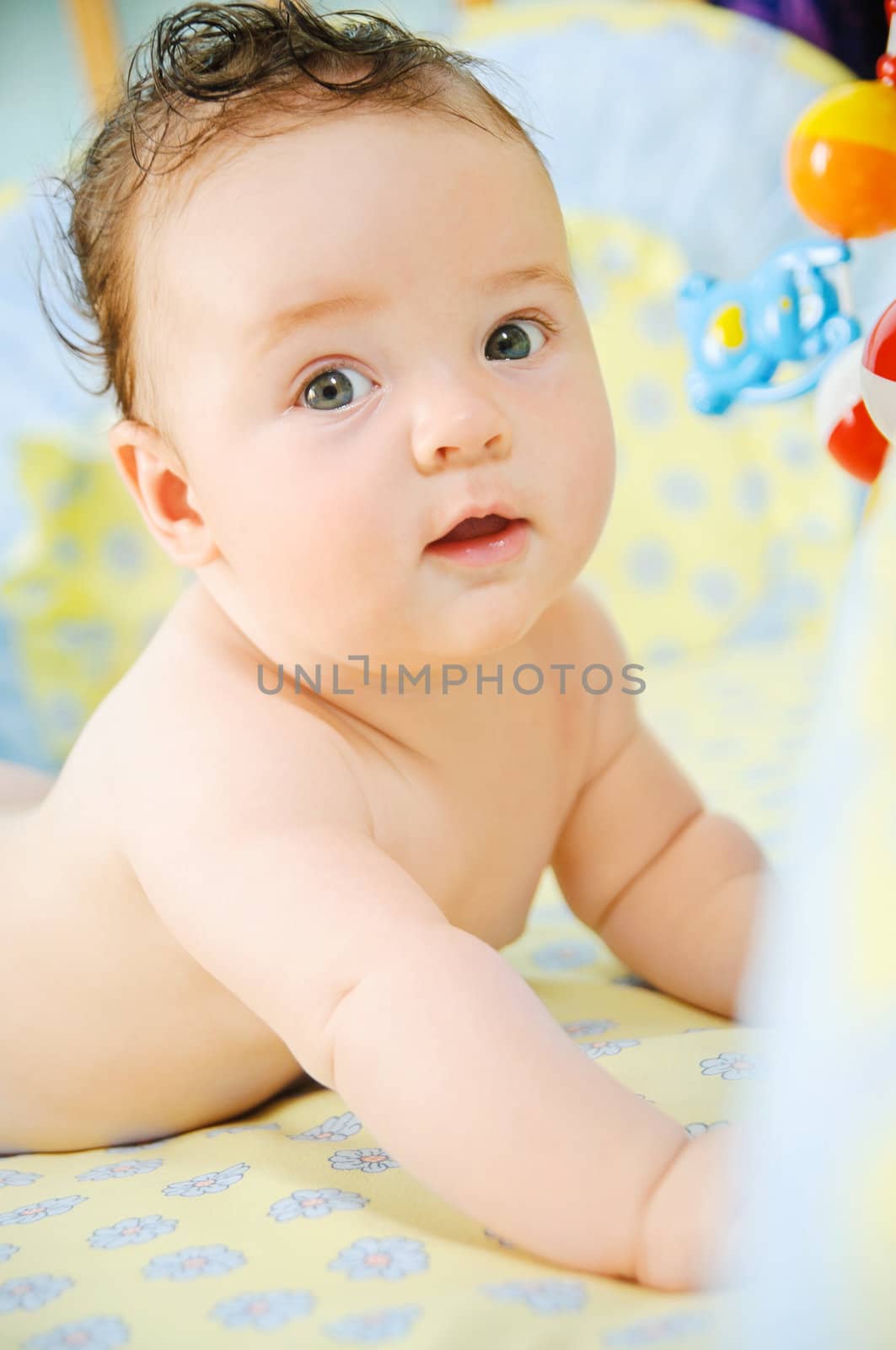 Beautiful cute baby boy is lying in a bed.