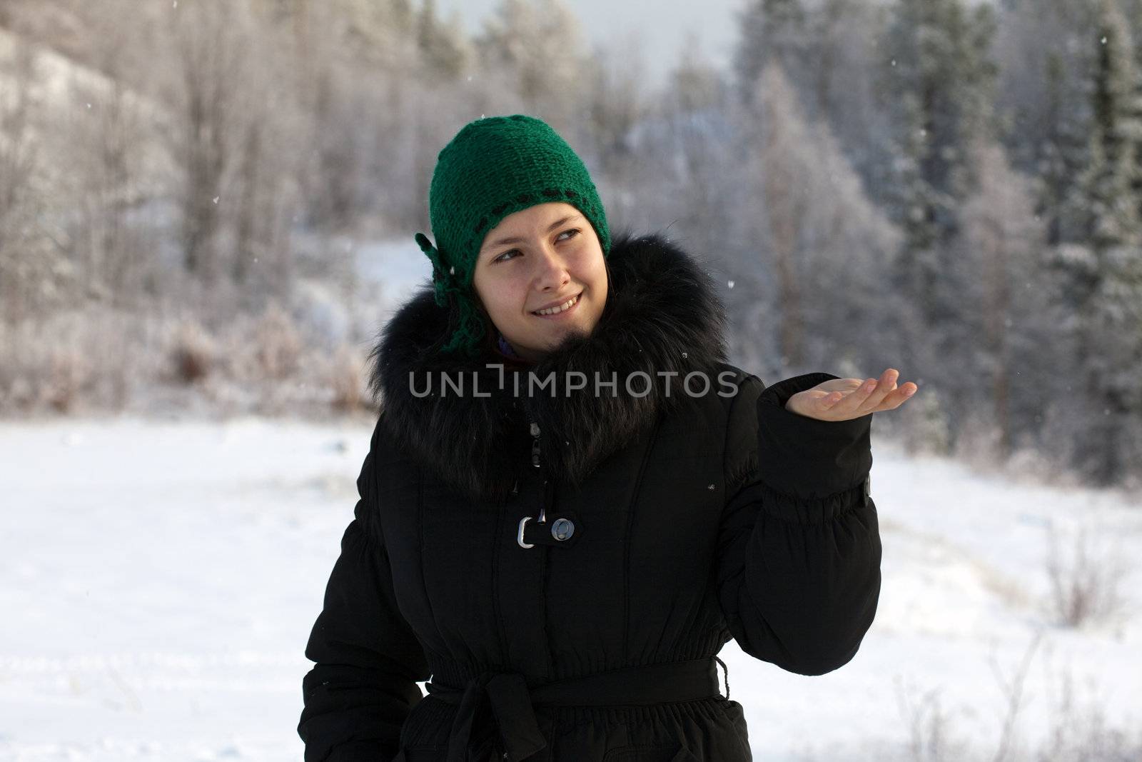 Girl catches snowflakes on the background of a winter forest