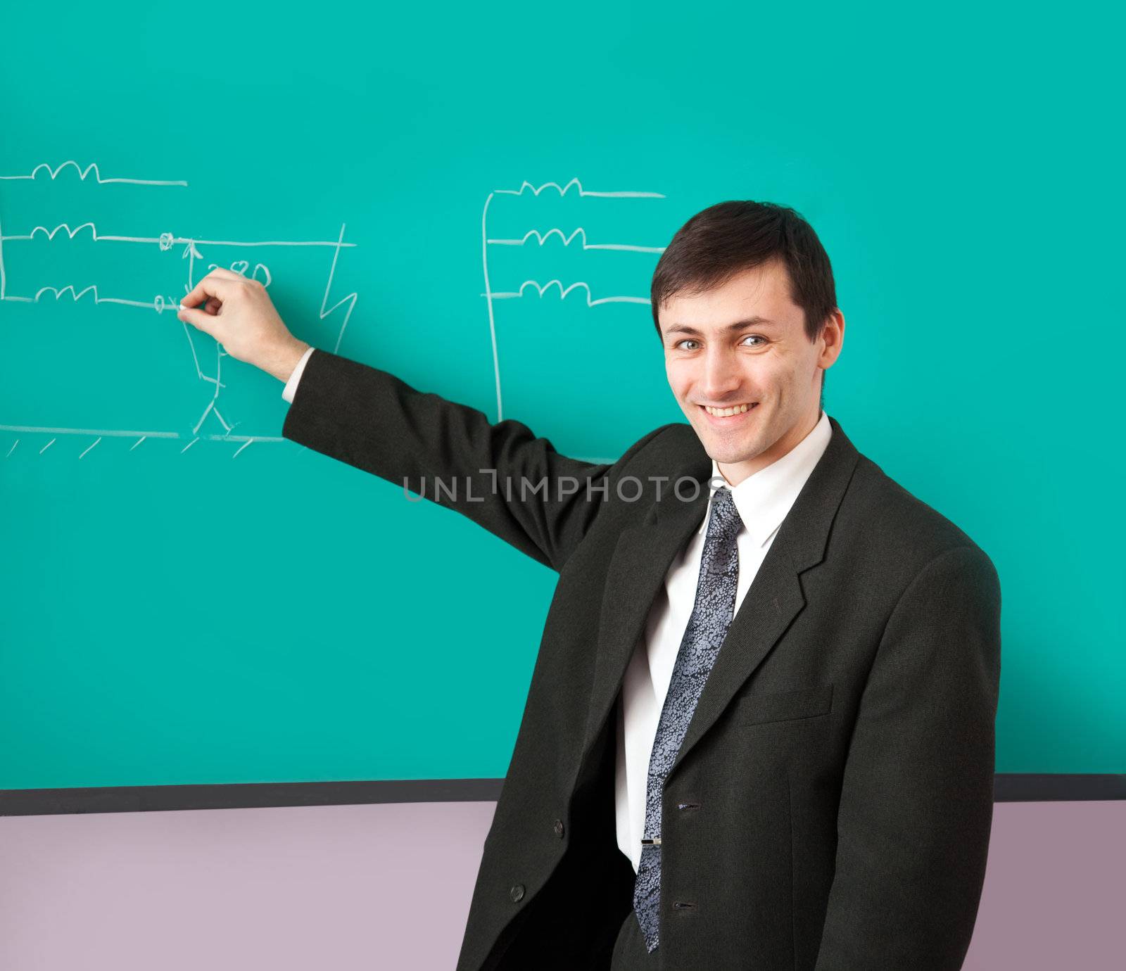 Young scientist giving a lecture on the background of the chalkboard with the scheme.