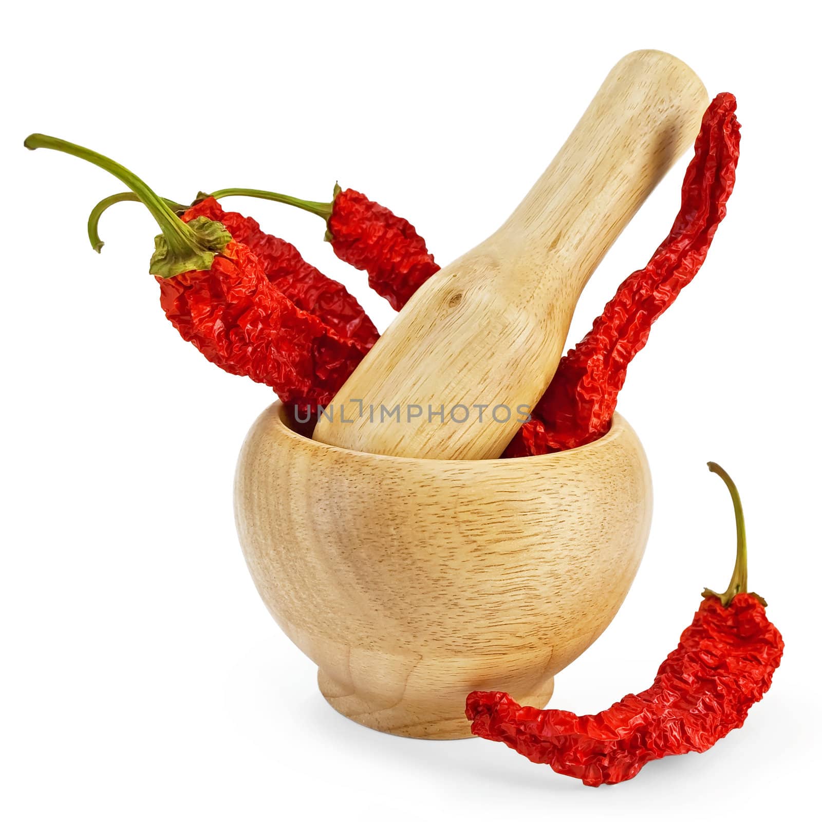 Three dry hot peppers in a wooden bowl and a pepper on the table isolated on white background