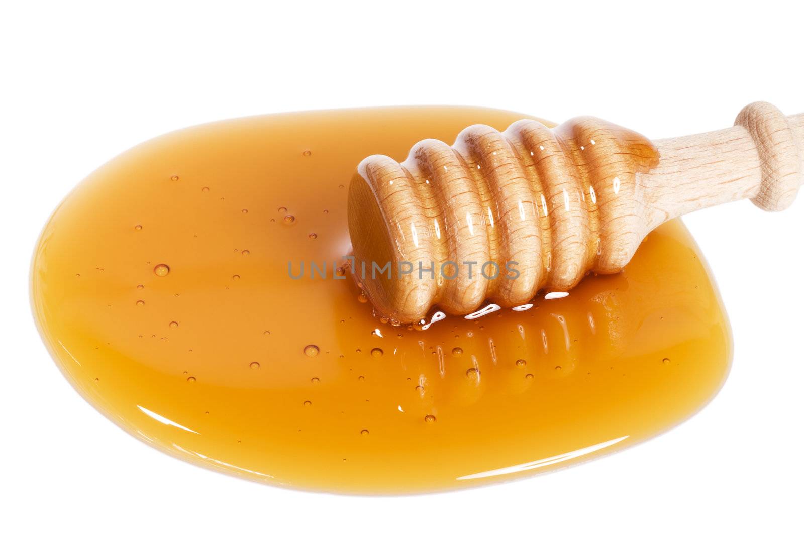 honey dipper from slightly top in a puddle of honey on white background
