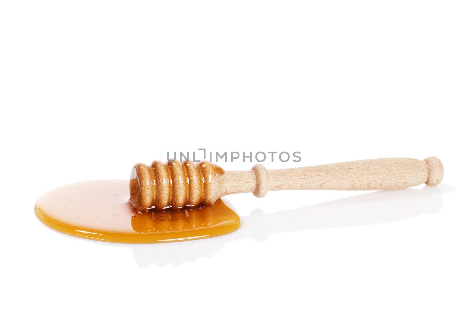 honey dipper in a puddle of honey on white background