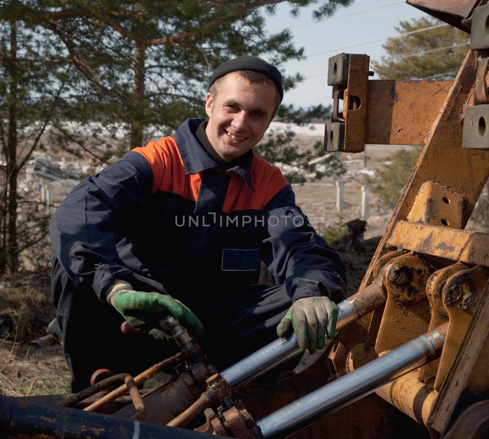 Machinist excavator with a wrench in his hand repairing a tractor