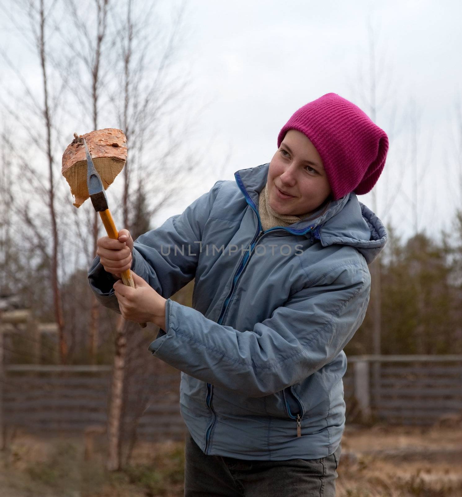 Girl cuts firewood with an ax. Country Landscape