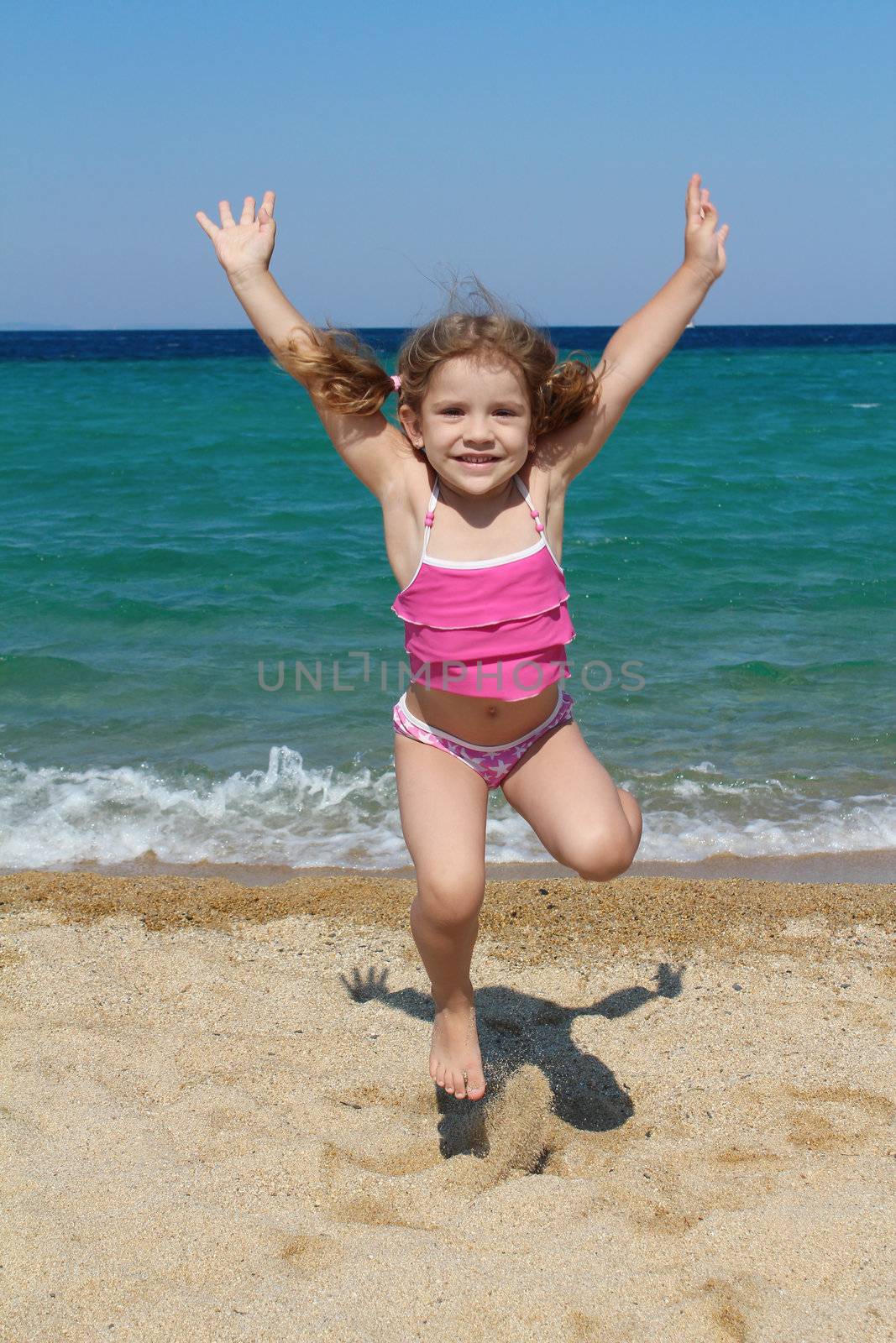 happy little girl jumping on the beach by goce