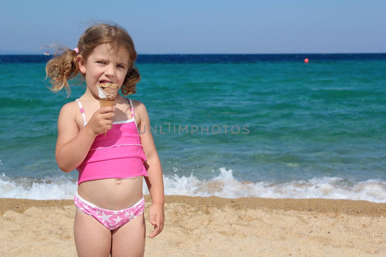 little girl eat ice cream on the beach by goce