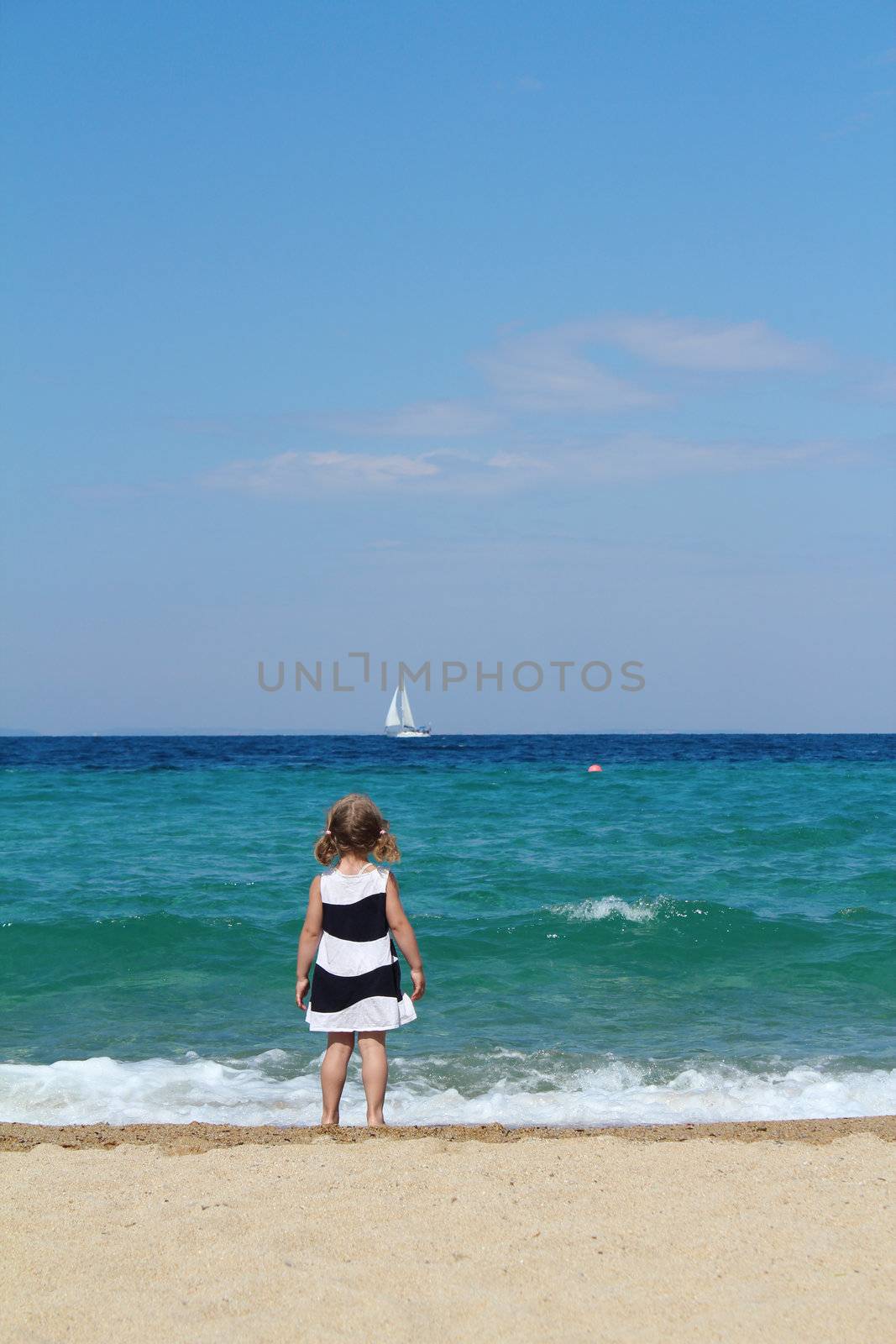 little girl looking boat at sea