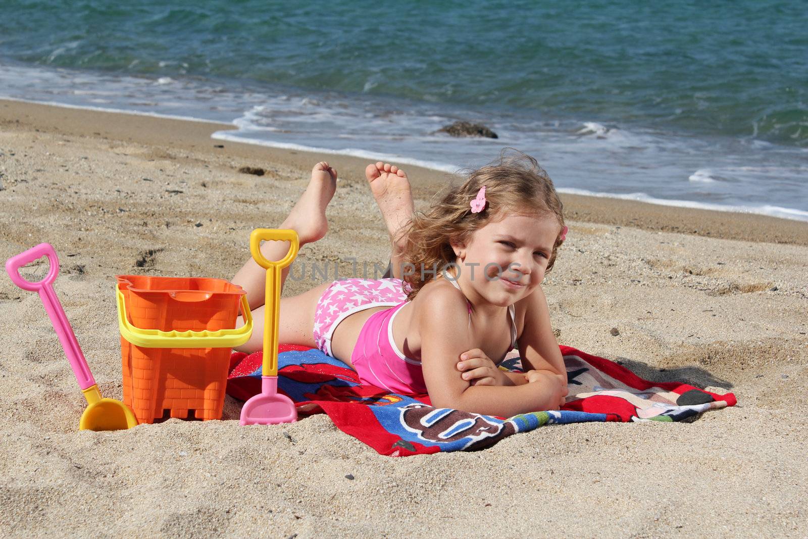 little girl lying on the beach by goce