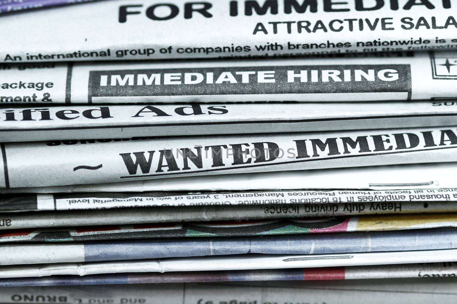stack of newspaper with Classified ads,immediate hiring,wanted signs.