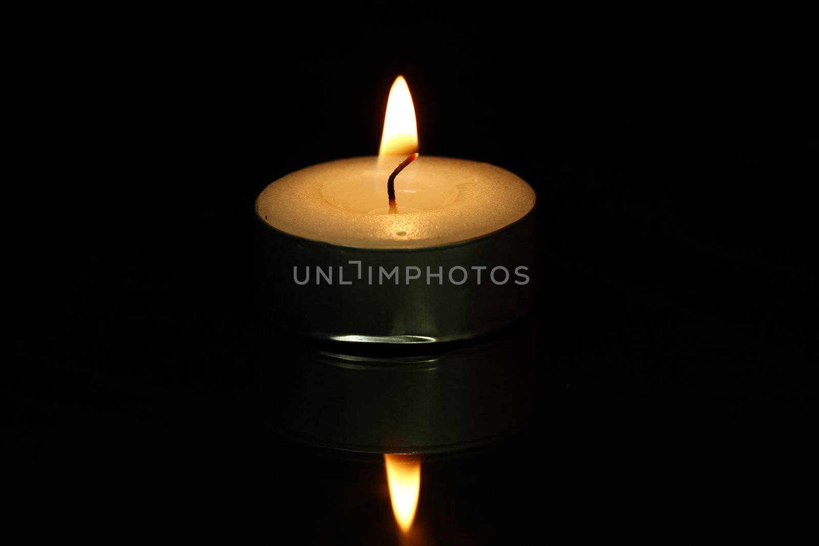 Small white candle with fire on a black background