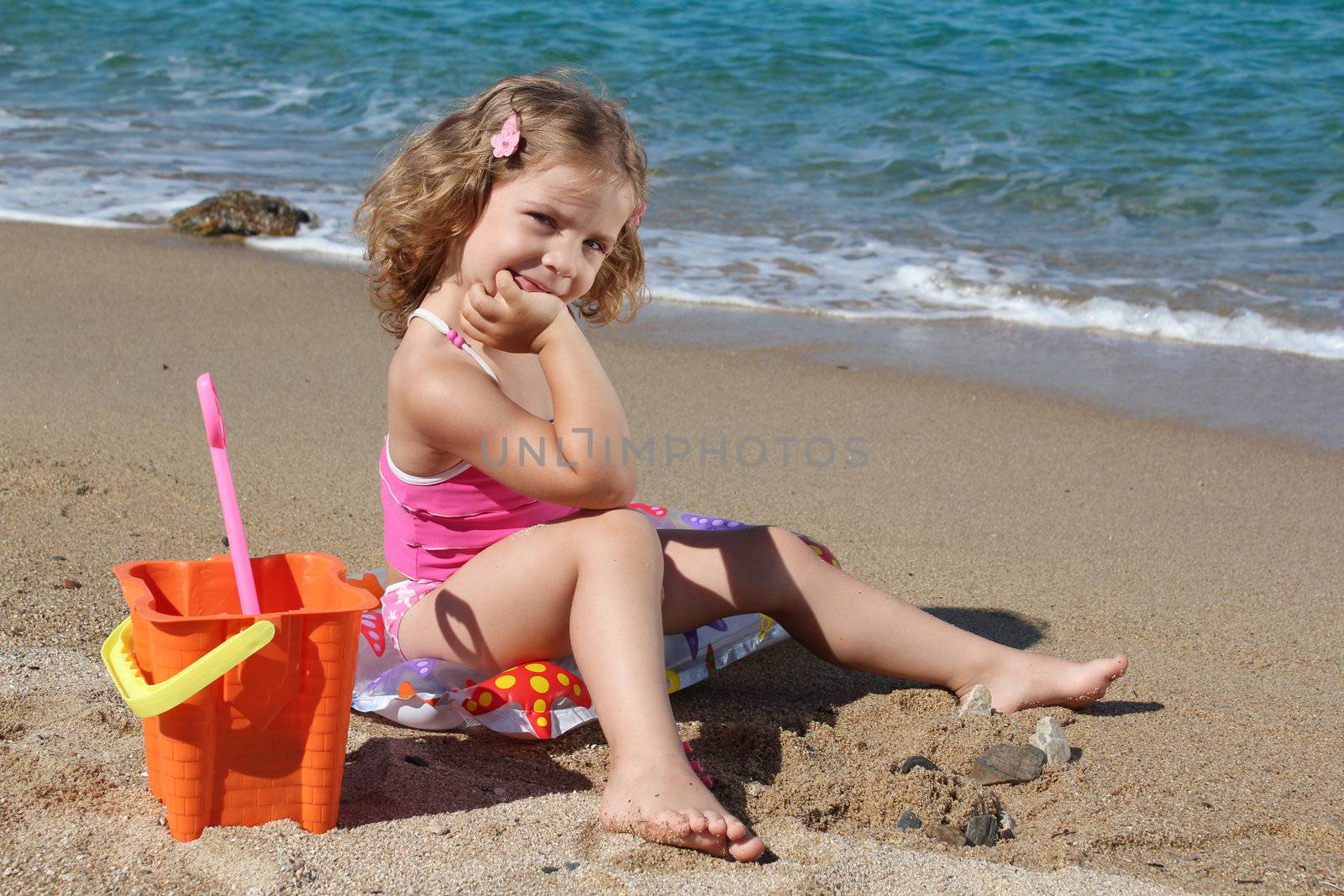 little girl with toys posing on the beach by goce