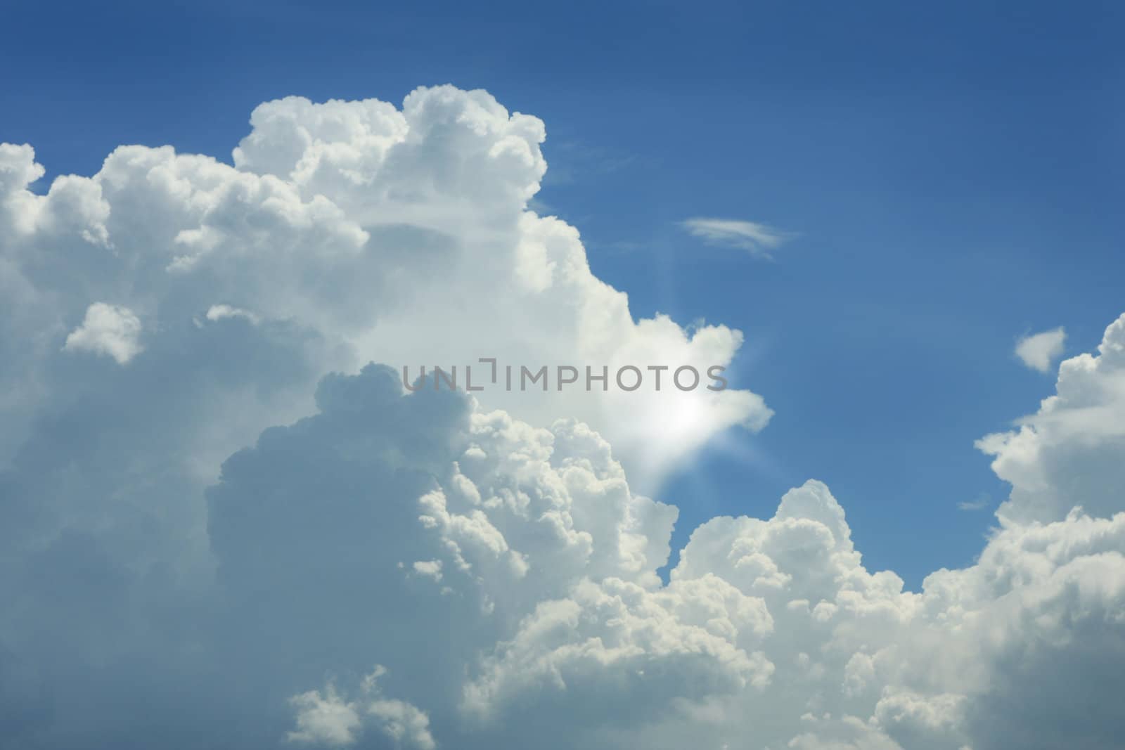 Dramatic blue sky with white clouds and sun.