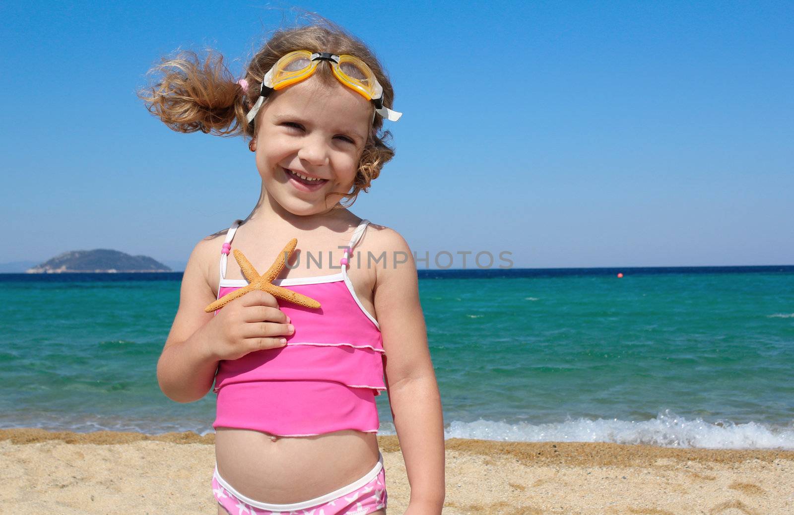 little girl with starfish posing on beach by goce