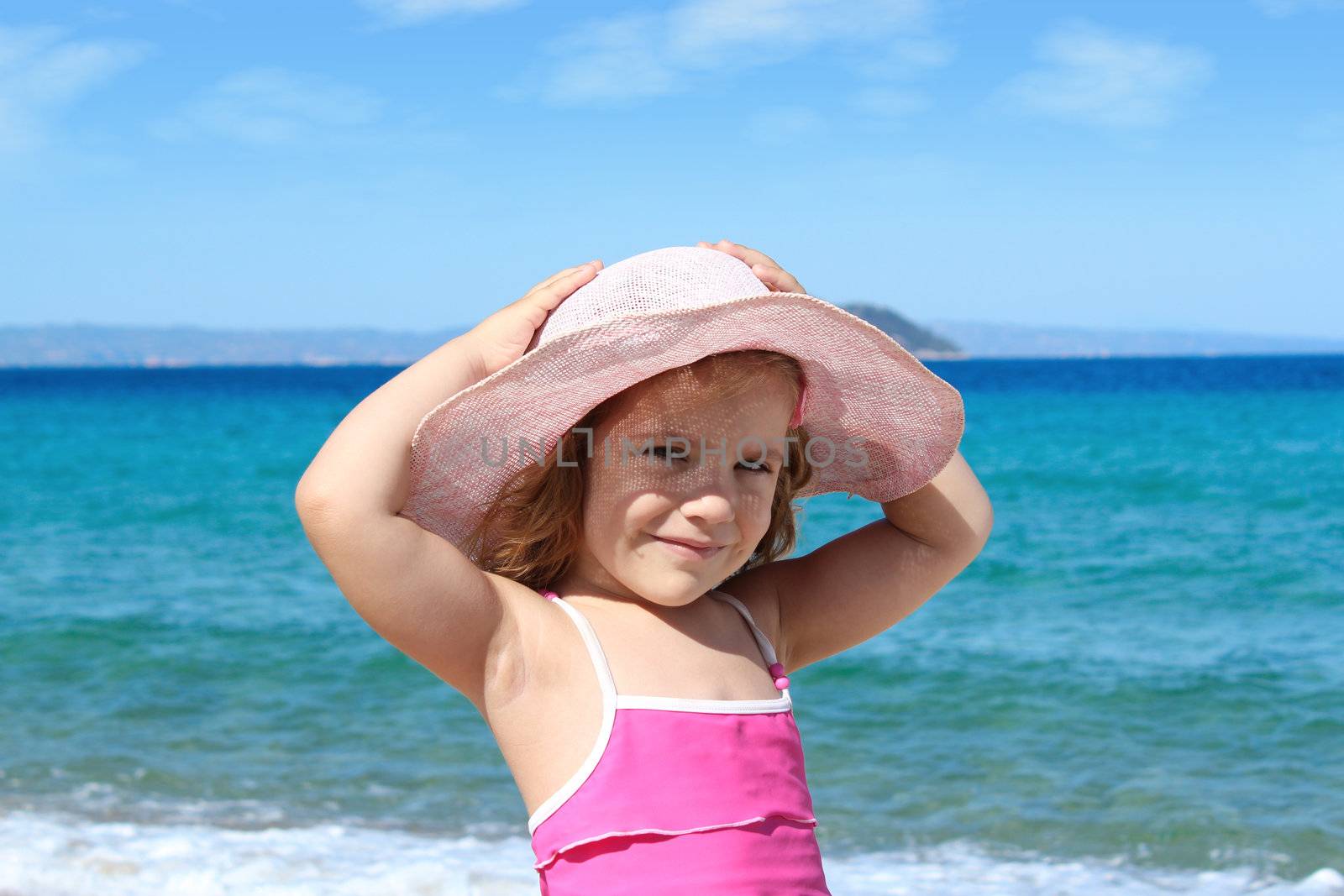 little girl with straw hat on beach by goce