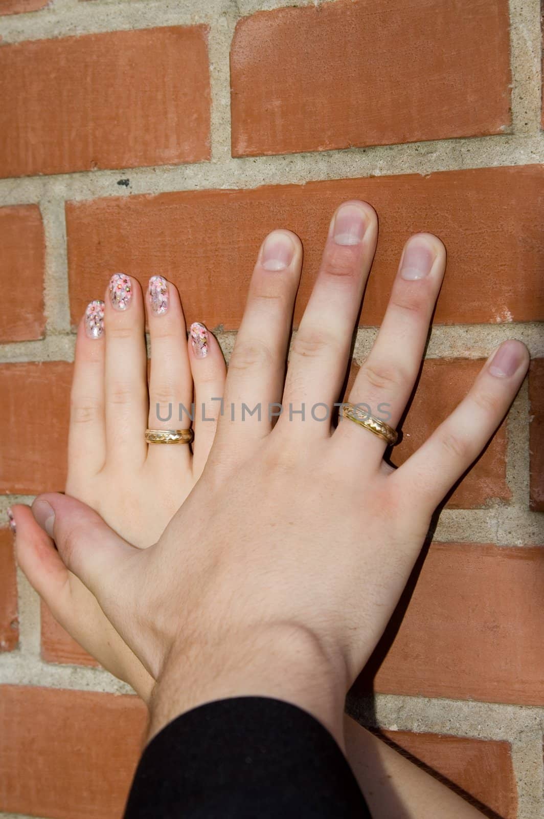 Hands with wedding rings on a brick wall
