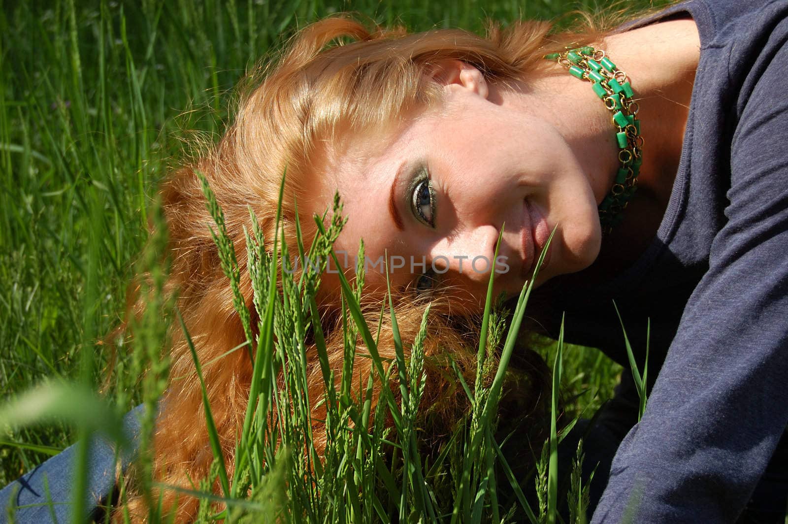 Beautiful redhead girl over high green grass