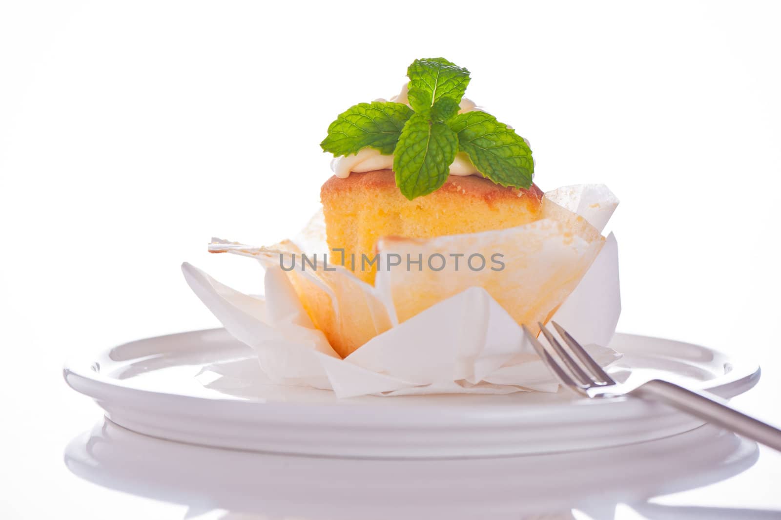 Cupcake with vanilla cream and mint leaf on a white background