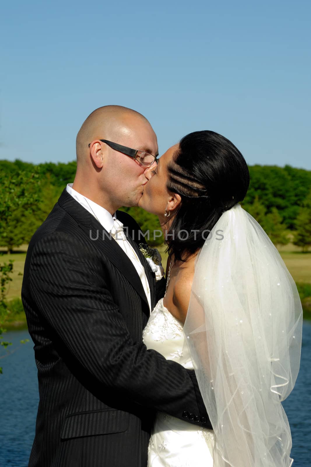 Bride and groom is kissing by the lake.