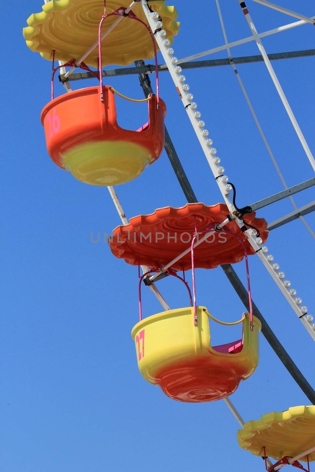 Giant orange and yellow colored wheel detail with its chairs by beautiful weather