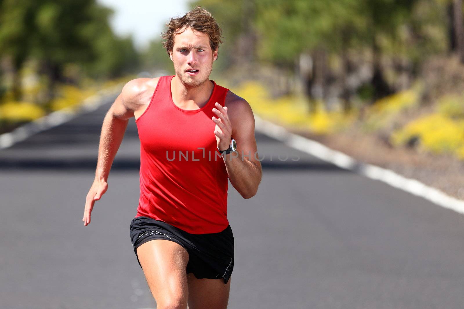 Running sport man. Fit muscular young male runner sprinting at great speed outdoors on road.