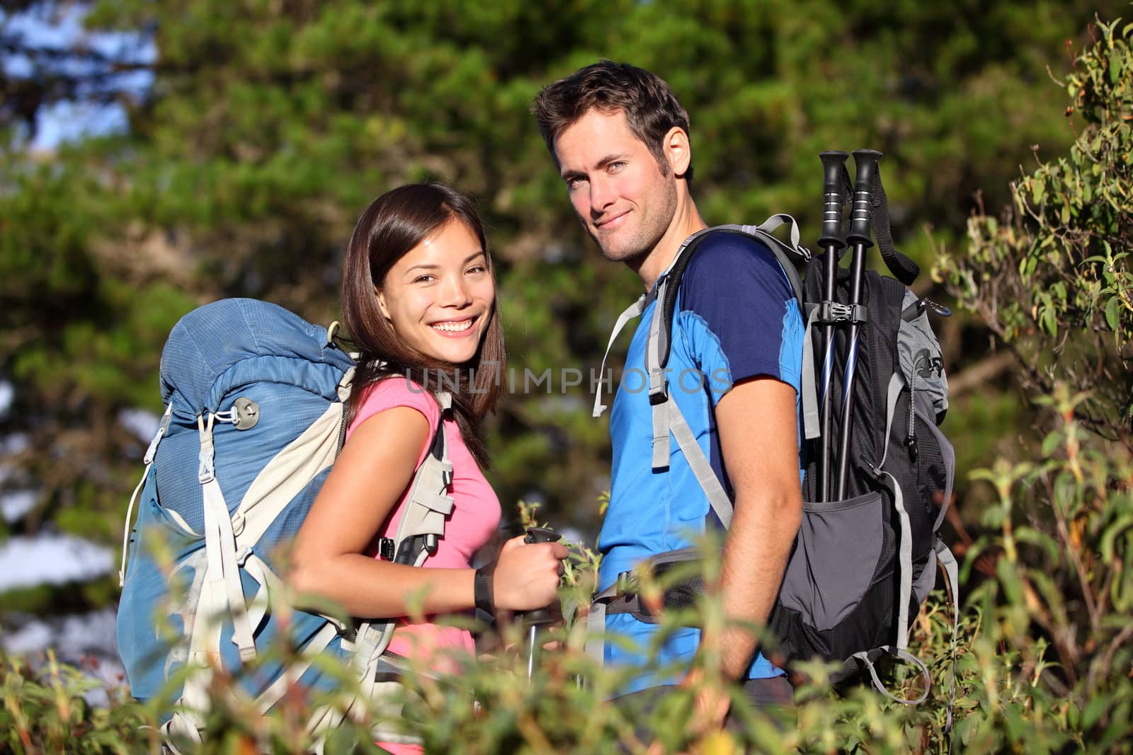 Happy hiking couple smiling during hike in forest on Tenerife, Canary Islands, Spain. Mixed race couple.