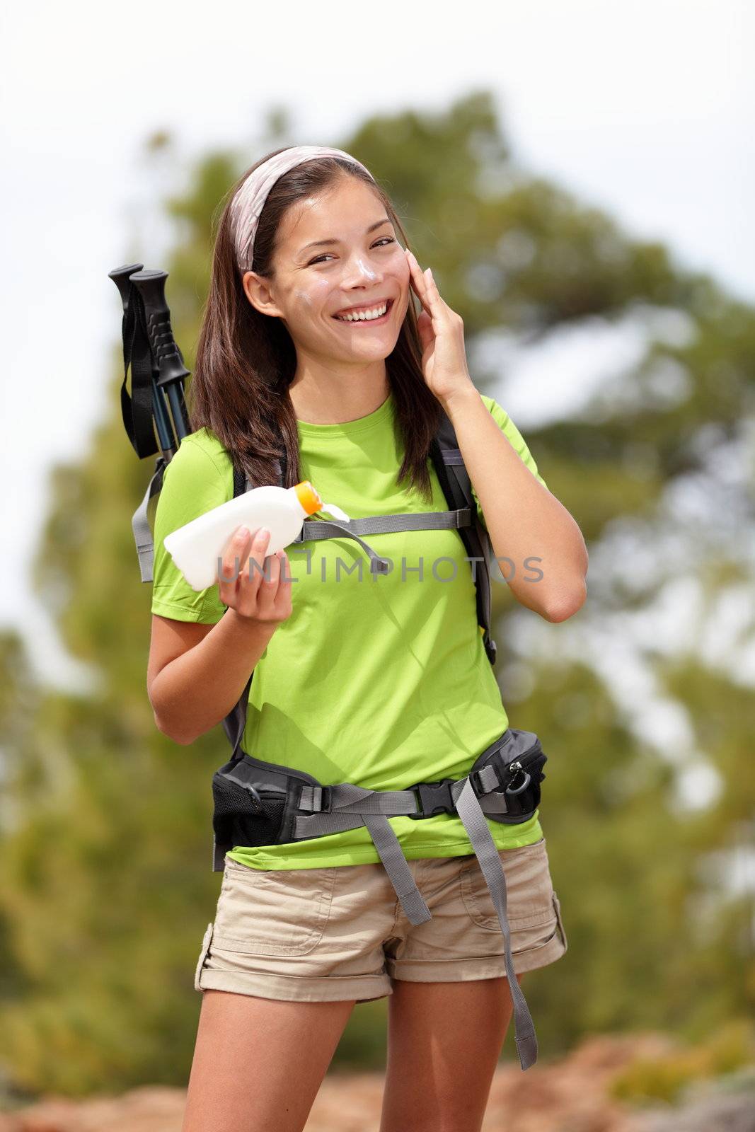 Sunscreen lotion woman. Woman hiking putting sun block lotion outside during summer hike vacation. Asian Caucasian female model.
