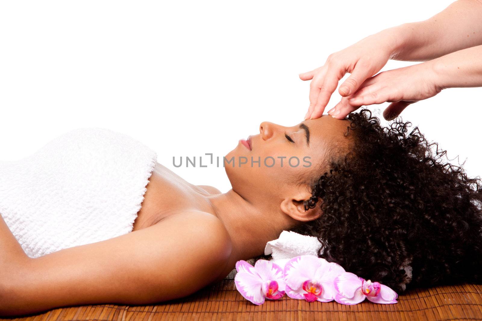 Beautiful happy peaceful sleeping woman at day spa, laying on bamboo massage table with head on pillow wearing a towel getting a facial massage, isolated.