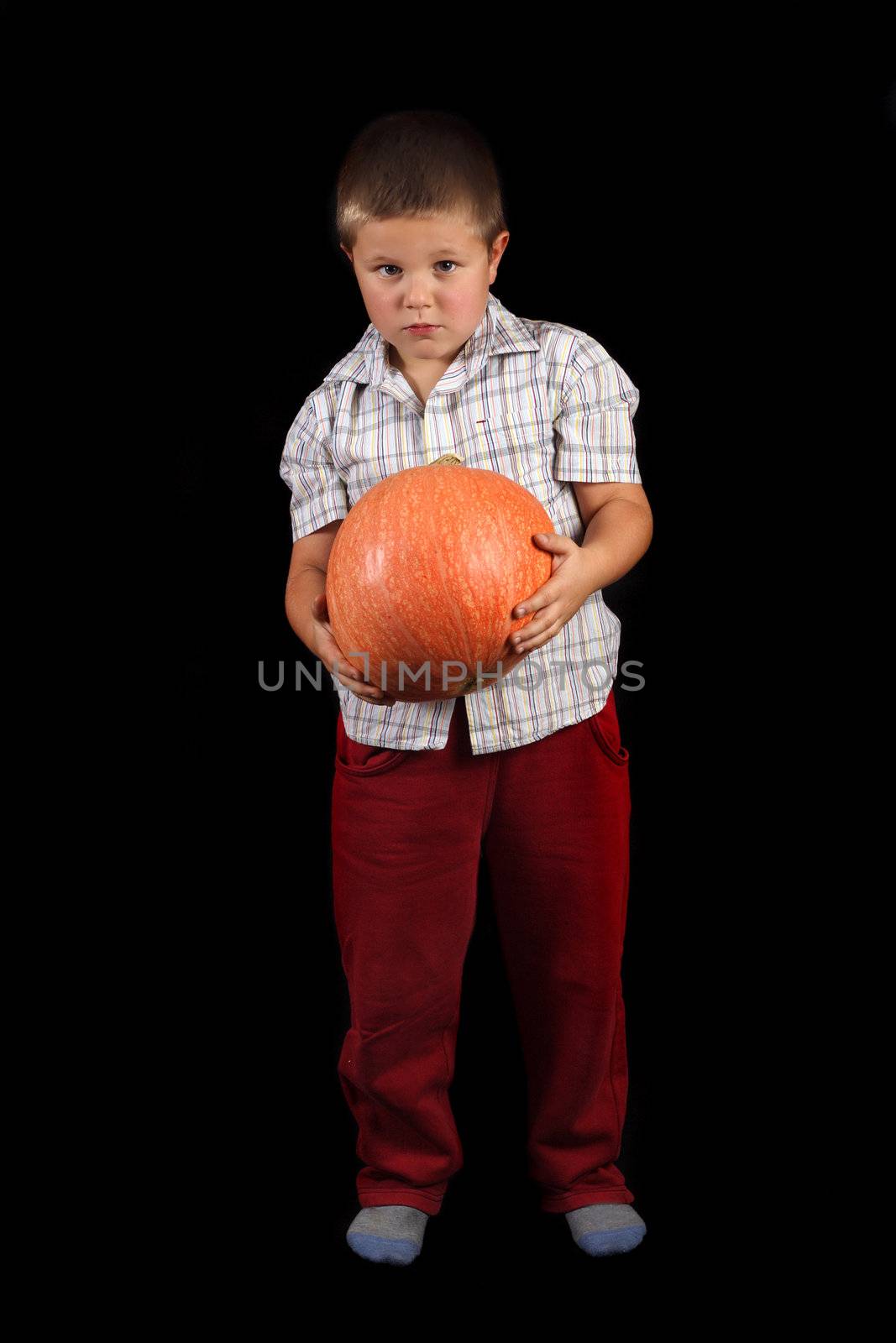 Boy is holding Halloweens orange pumpkin photo on the black background