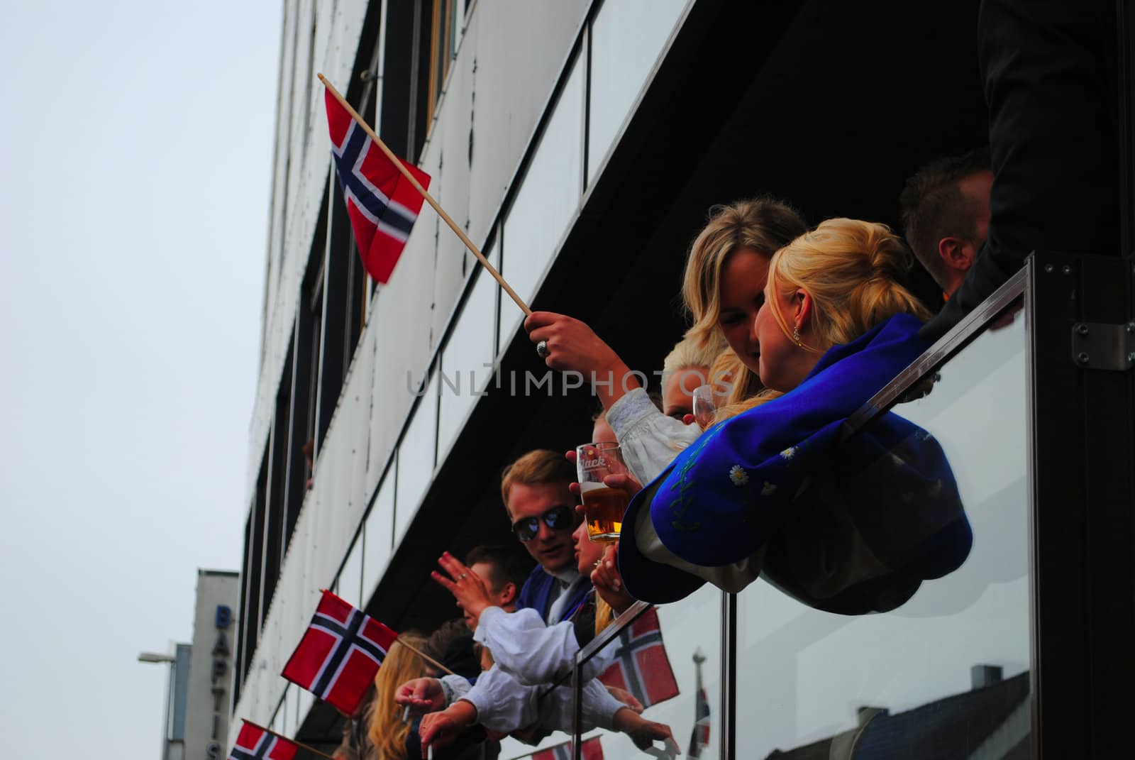 Happy norwegians watching the national day parade from a pub.
