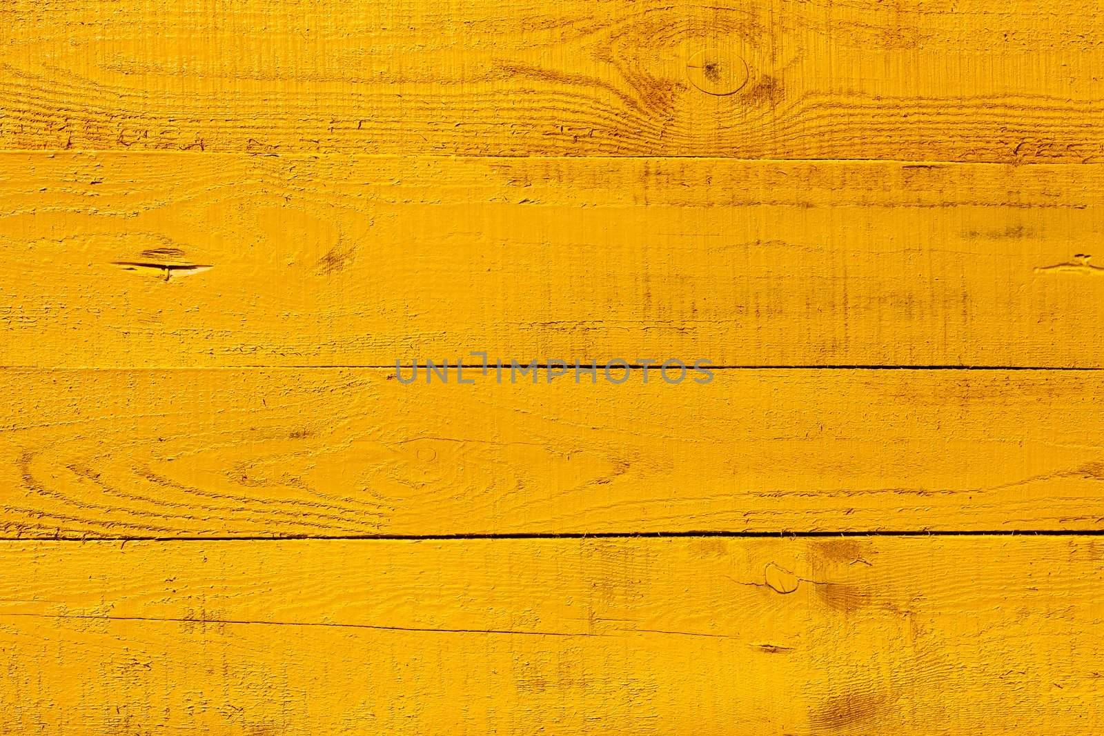 Detail of wooden fence. Four horizontal boards freshly painted  in bright yellow