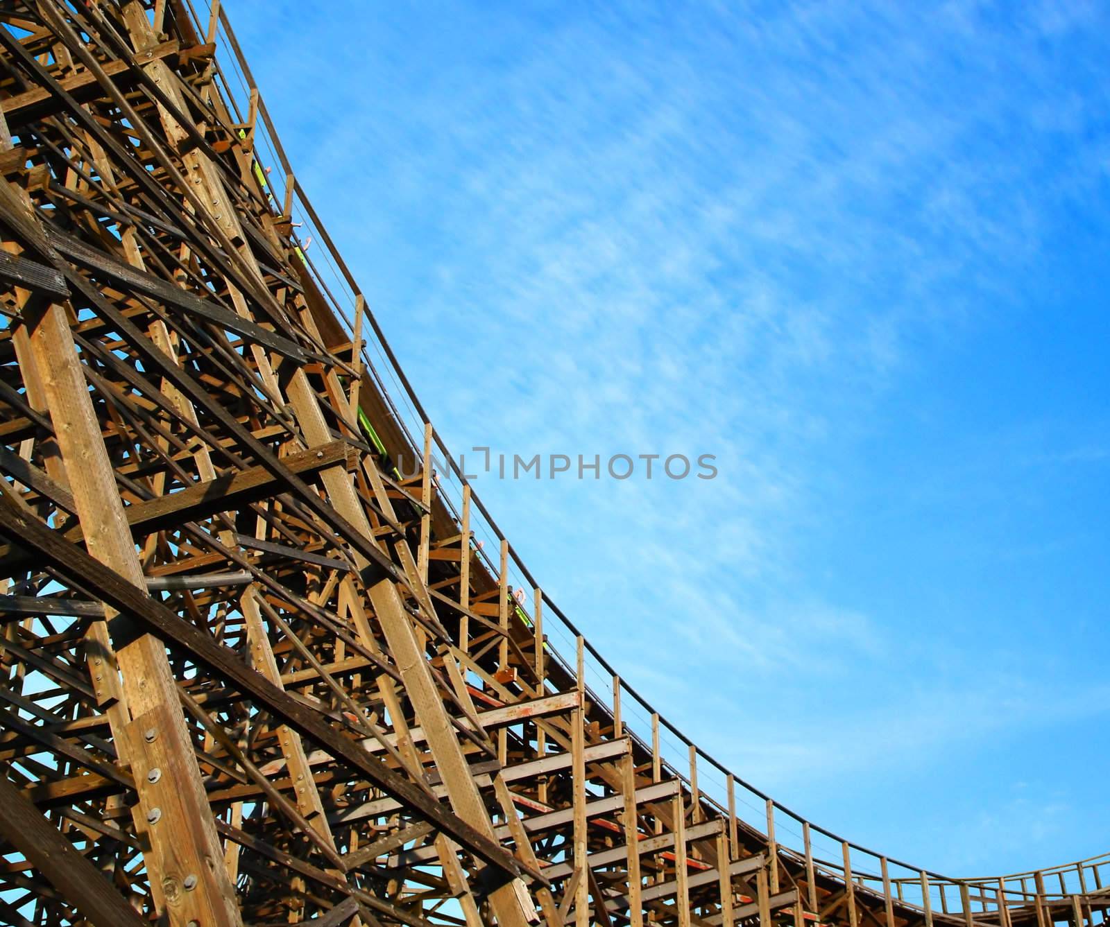 Scary joy ride down an old giant wooden roller coaster on a beautiful day at the amusement park.