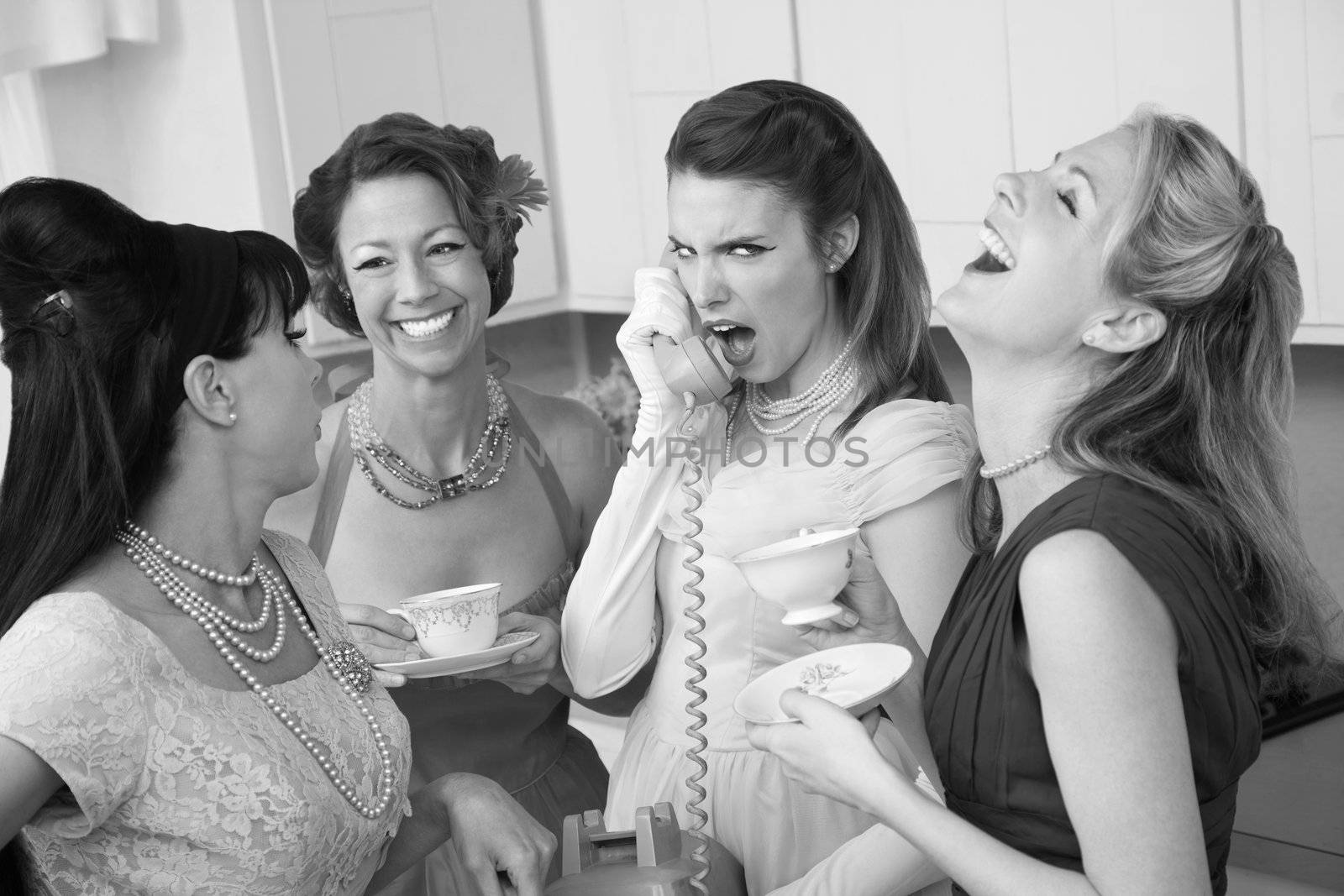 Outraged woman on phone with three friends in a kitchen