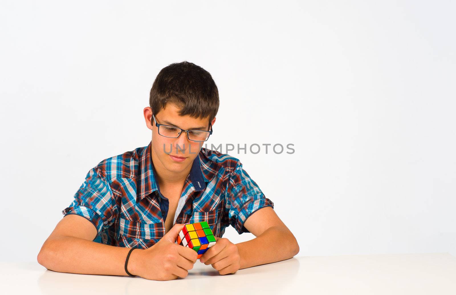 Teenager with glasses concentrated playing with a cube