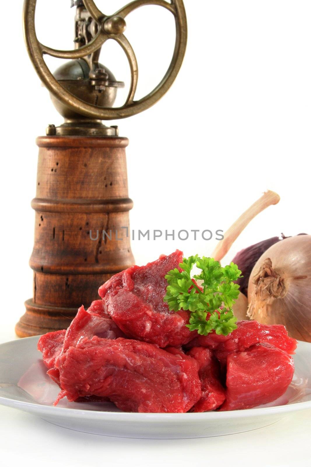 raw beef stew with parsley on a white plate