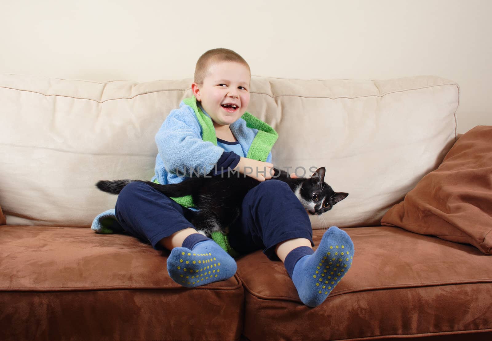 small boy with cat sits on sofa