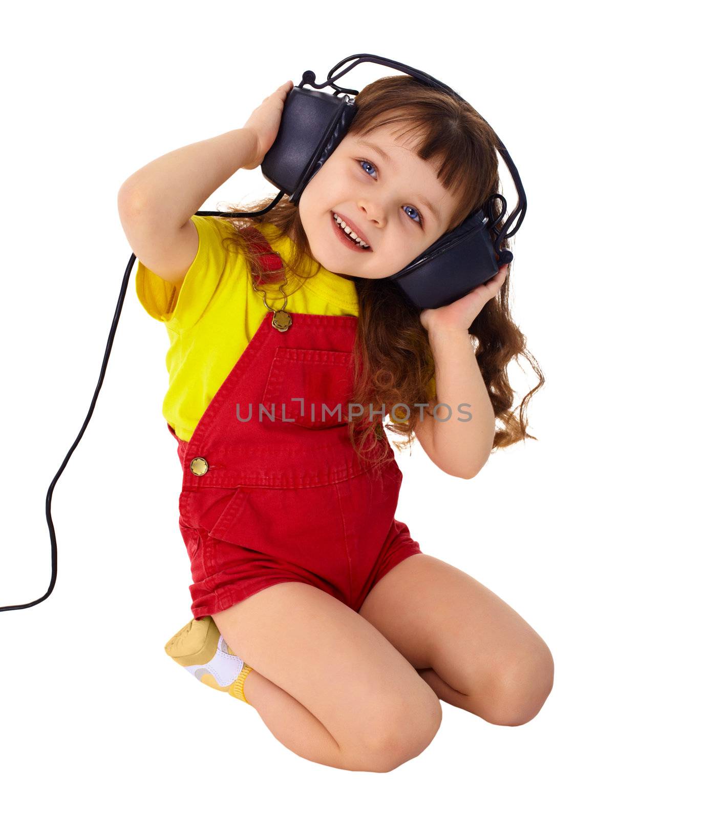 A little girl enjoys music in big headphones isolated on white background