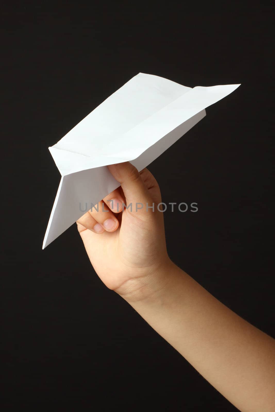 Child hand with paper plane over black background