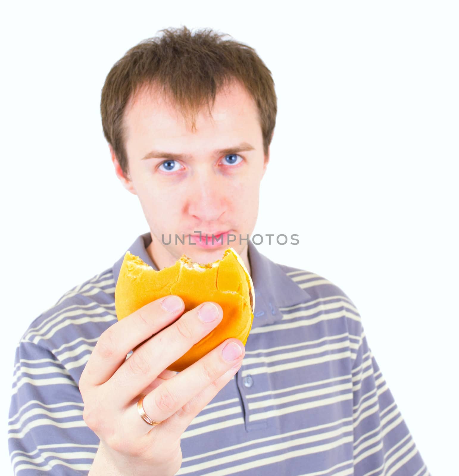 The young man eats a hamburger. Focus on hamburger.